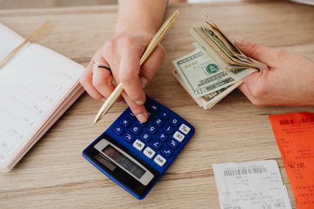 person using a blue calculator when counting cash